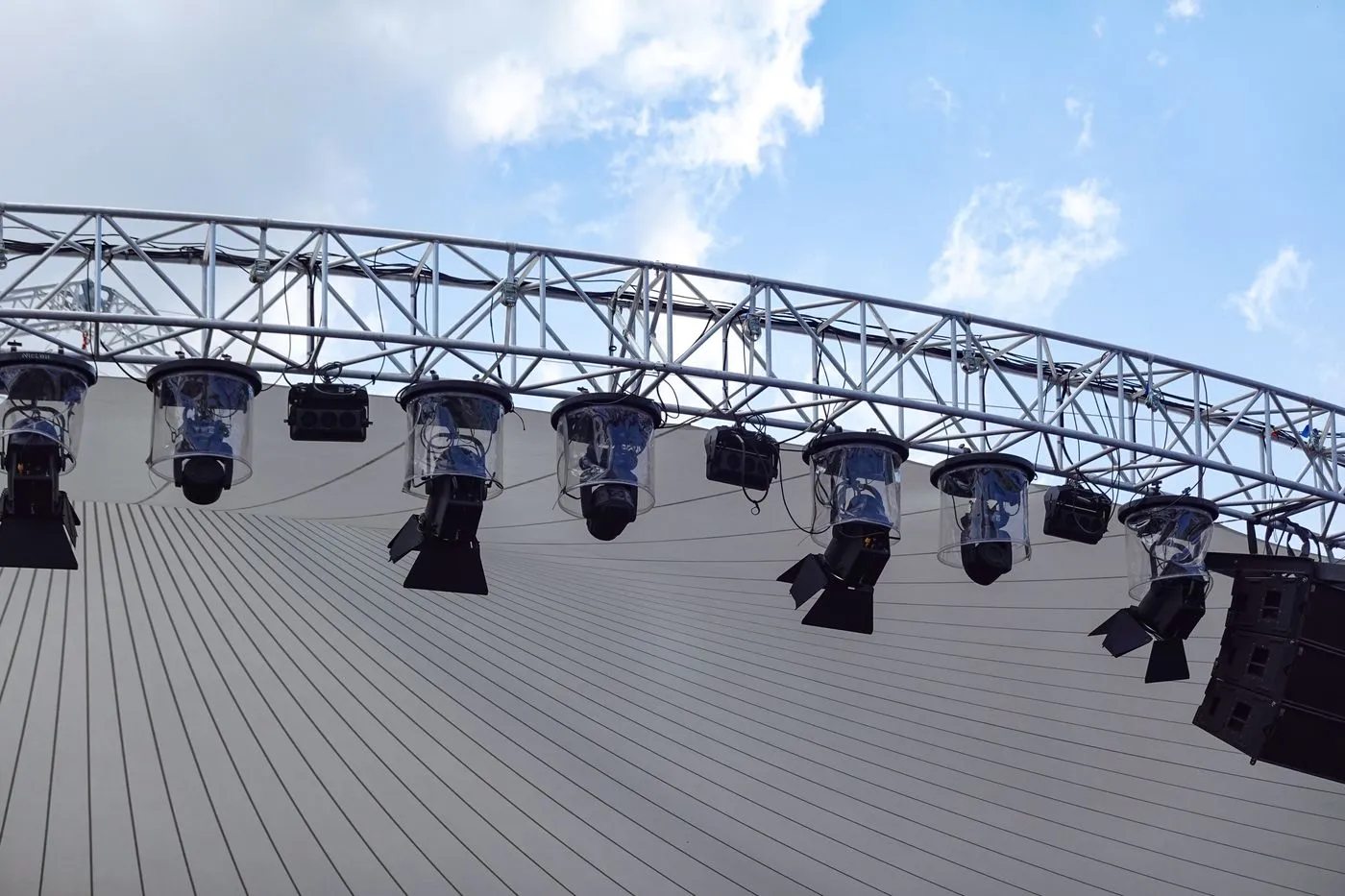 Lighting fixtures hung on an outdoor truss against the sky